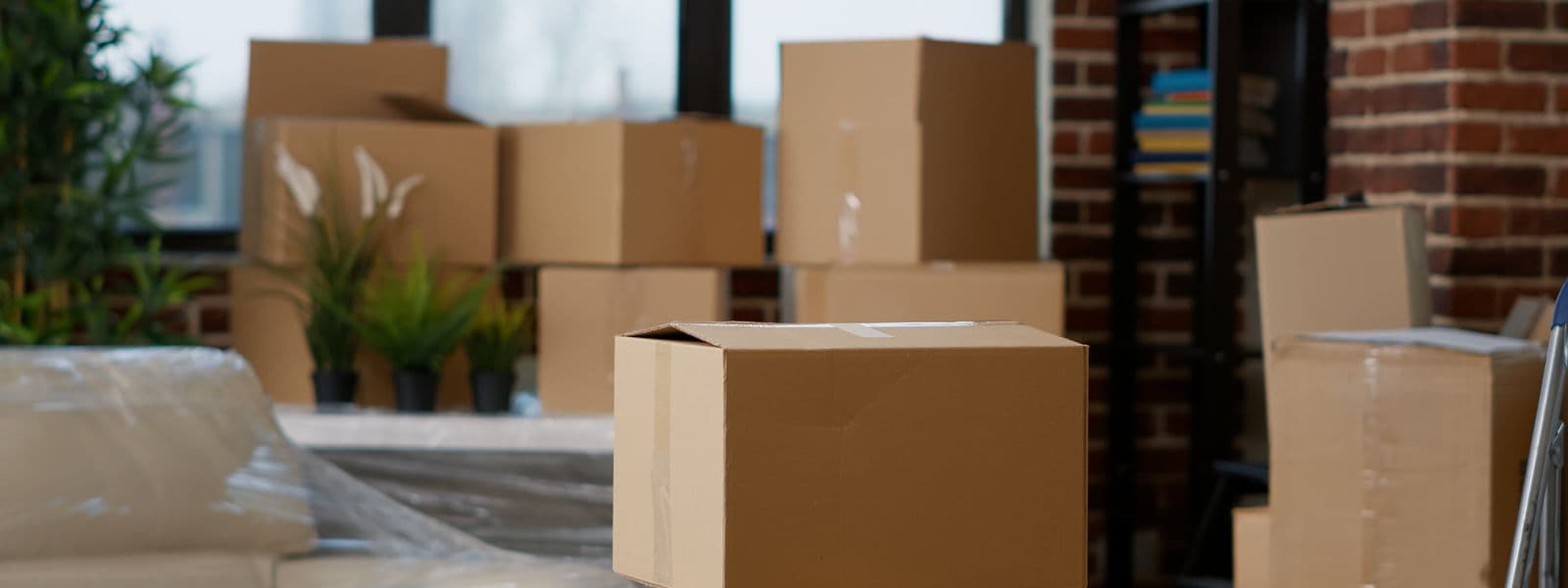 Umzugskartons und eingepackte Möbel in einer geräumten Wohnung