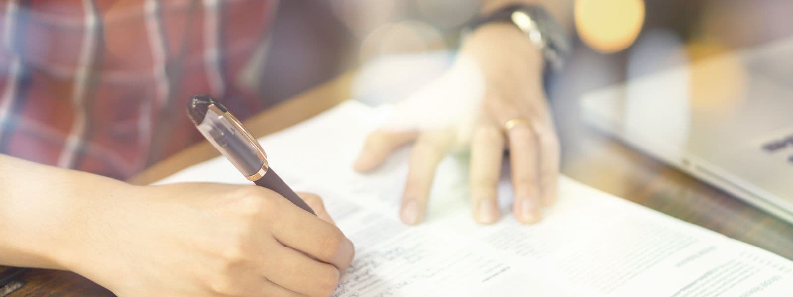 Eine Hand füllt ein Formular an einem Schreibtisch aus